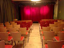 Blick vom Zuschauerraum mit leeren Stühlen auf die Bühne des Theater JARO.
